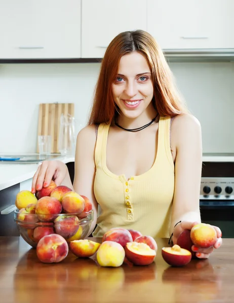 Beautiful woman with peaches at table — Stock Photo, Image