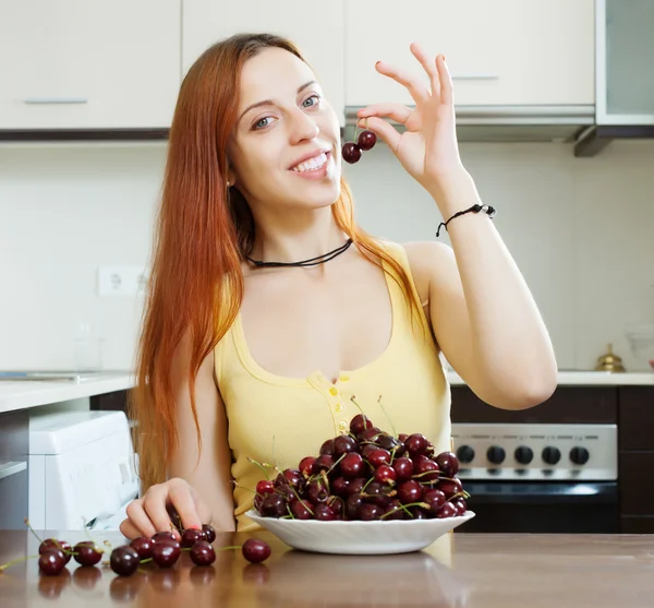 Женщина с вишней на домашней кухне — стоковое фото