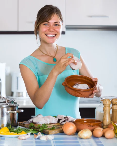 Mujer cocinando merluza en olla de cerámica — Foto de Stock