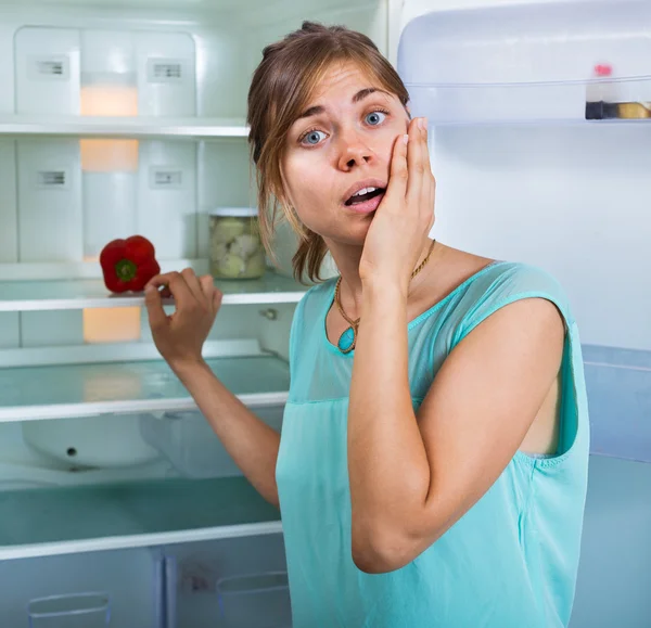 Женщина смотрит на пустой холодильник — стоковое фото
