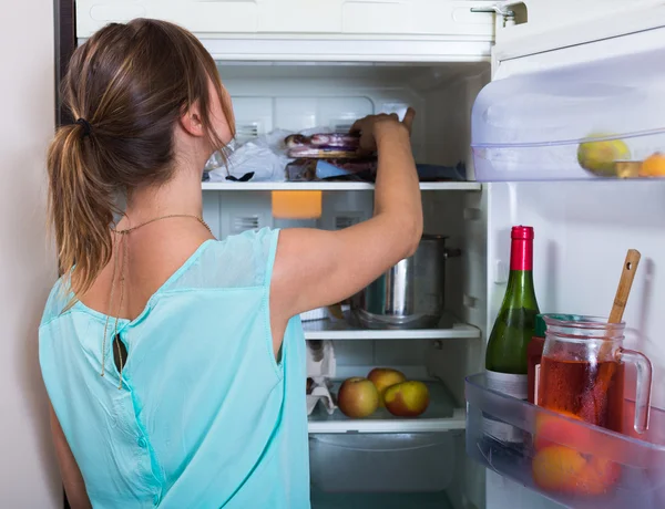Vrouw in de buurt van volledige koelkast — Stockfoto