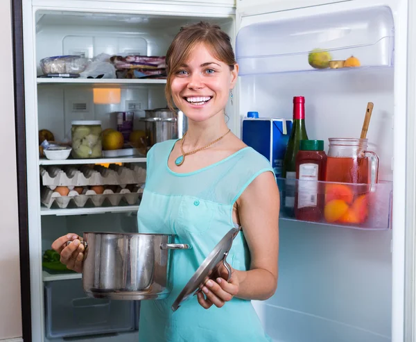 Sorrindo mulher perto da geladeira completa — Fotografia de Stock