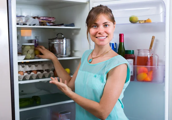 Усміхнена жінка біля повного холодильника — стокове фото