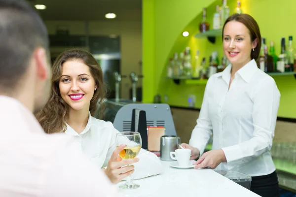 Vrouwelijke barista en twee cliënten in café — Stockfoto