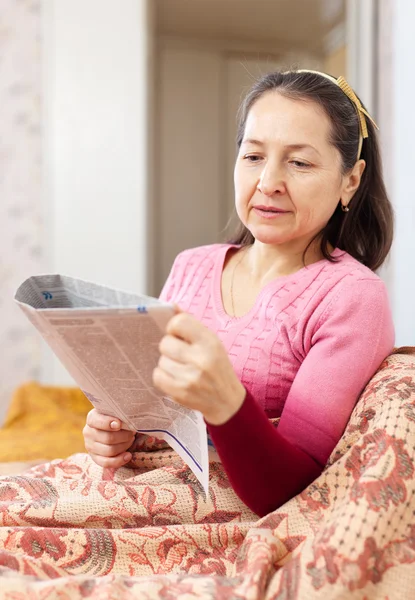 Kvinnan läser tidningen hemma — Stockfoto