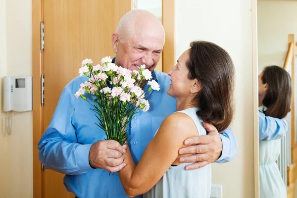 Senior man came to mature woman with flowers — Stock Photo, Image