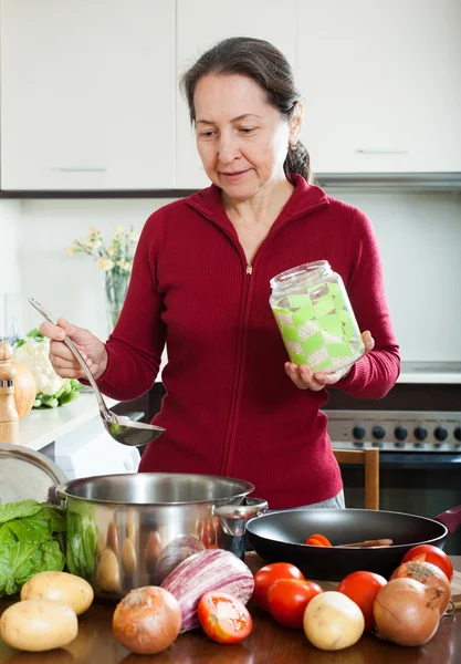 Mogen kvinna matlagning soppa med ris — Stockfoto