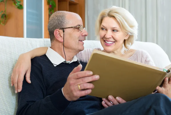 Senior spouses with picture album indoors — Stock Photo, Image