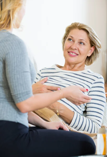 Giovane donna che allatta anziana femmina — Foto Stock