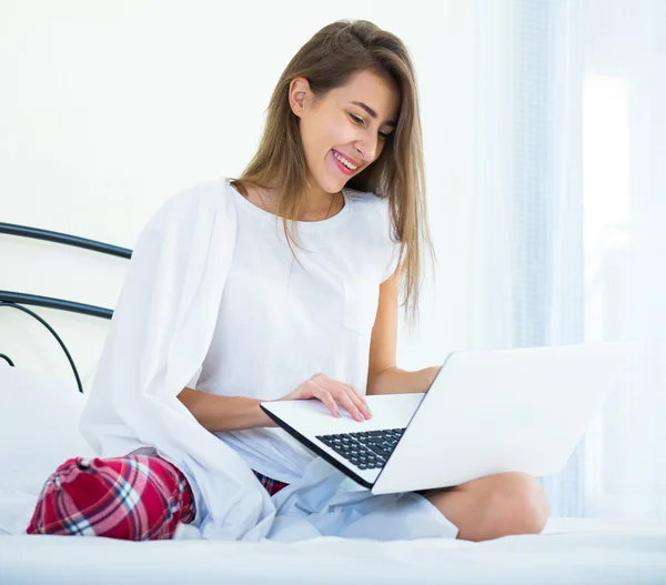 Student tjej studerar med laptop i sängen — Stockfoto