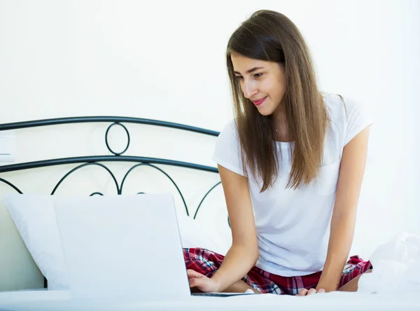 Étudiante fille cloutage avec ordinateur portable dans le lit — Photo
