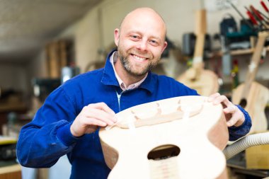 Successful guitar maker in workshop clipart