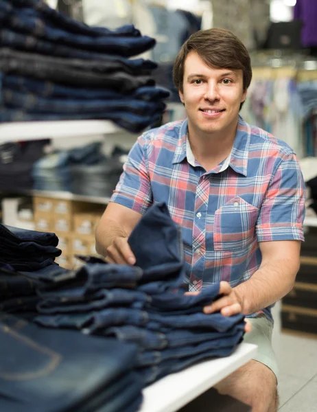 Masculino escolhe jeans na loja de roupas — Fotografia de Stock