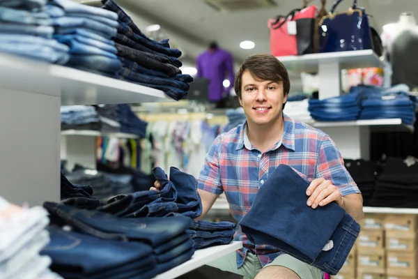 Мужчина выбирает джинсы в магазине одежды — стоковое фото