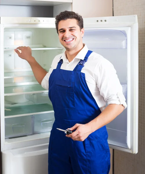 Handyman repairing refrigerator in kitchen — Stock Photo, Image