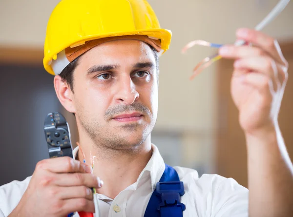 Handyman in helmet working with wires — Stock Photo, Image