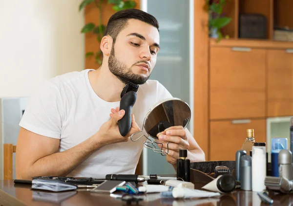 Guy looking at mirror and shaving beard — Stock Photo, Image