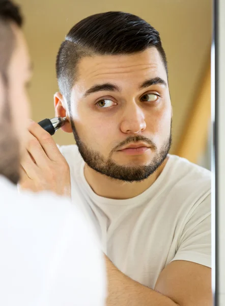 Man trims ear hair at home — Stock Photo, Image