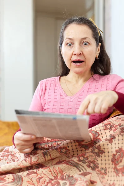 Skrämseln och förvånad kvinna med tidningen — Stockfoto