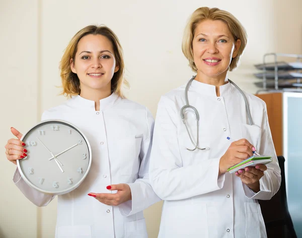 Vrouwelijke artsen met tijd in klok — Stockfoto