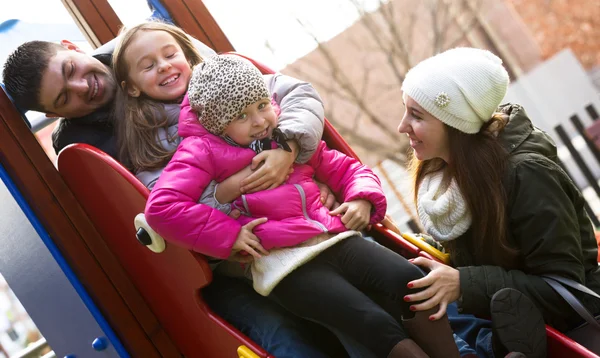 Family of four at children's playground — Stock Photo, Image