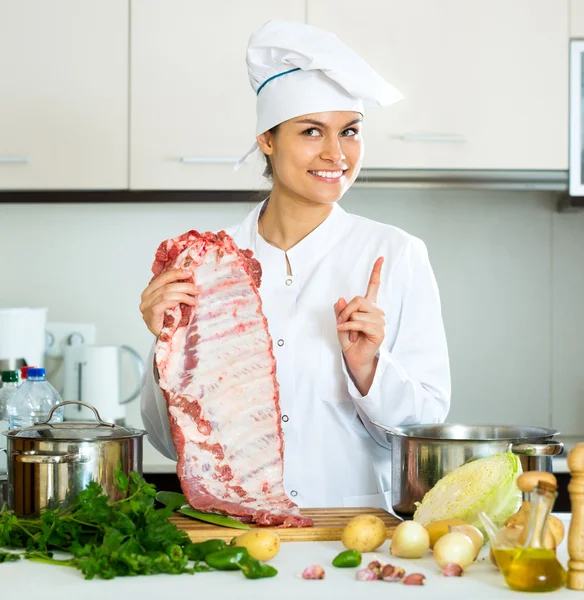 Жіночий шеф-кухар, що працює зі свинячими ребрами — стокове фото