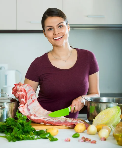 Happy young woman cooking meat