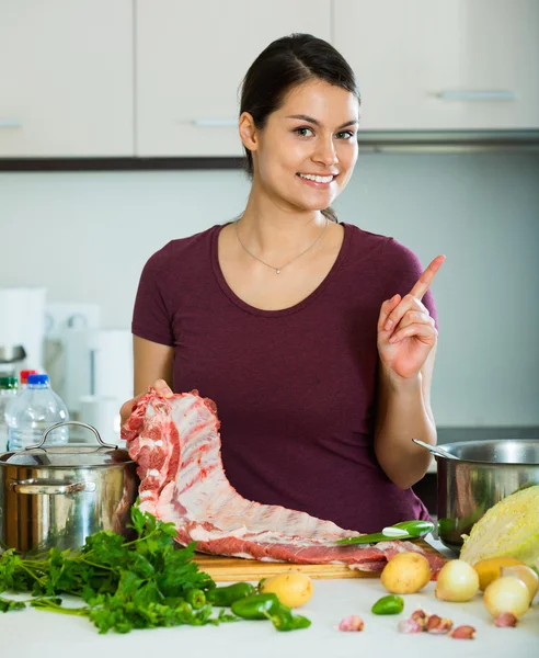 Giovane donna allegra cucinare carne — Foto Stock