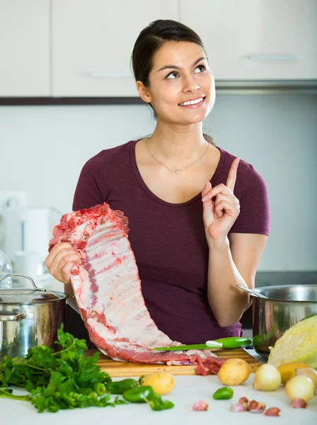 Веселая молодая женщина готовит мясо — стоковое фото