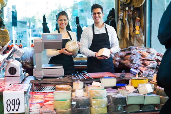 Two workers selling cheese and sausages — Stock Photo, Image
