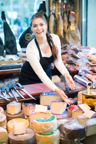 Cheerful young shopgirl selling cheese — Stock Photo, Image