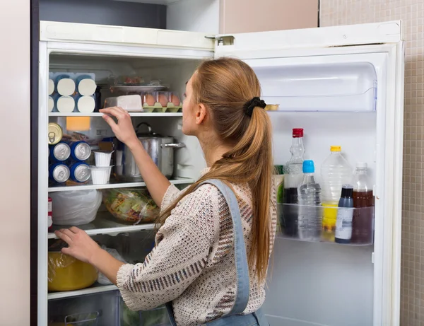 Accurate and positive girl standing near fridge — Stock Photo, Image