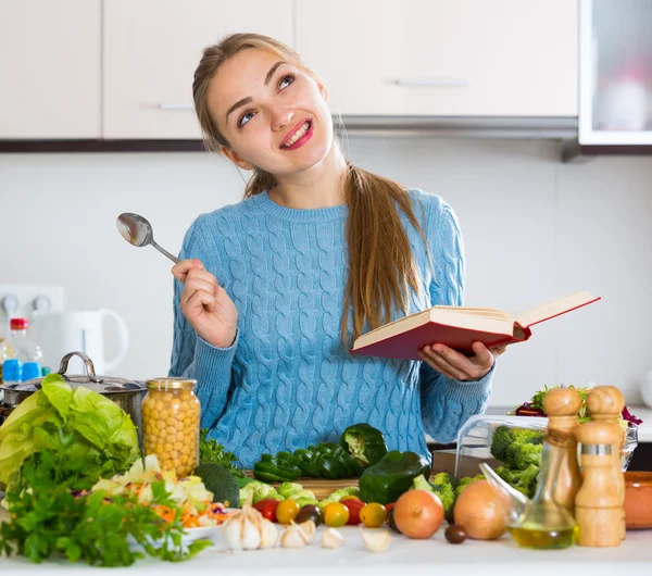 Kobieta z książki i warzywa w domu — Zdjęcie stockowe