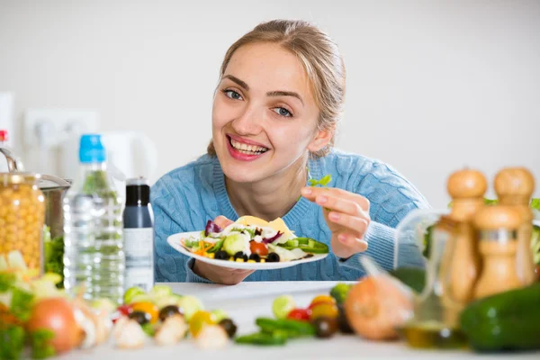 Улыбающаяся девушка украшает салат на тарелке — стоковое фото