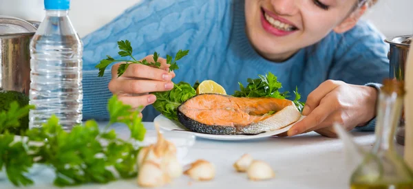 Girl decorating fried fish with herbs — Stock Photo, Image