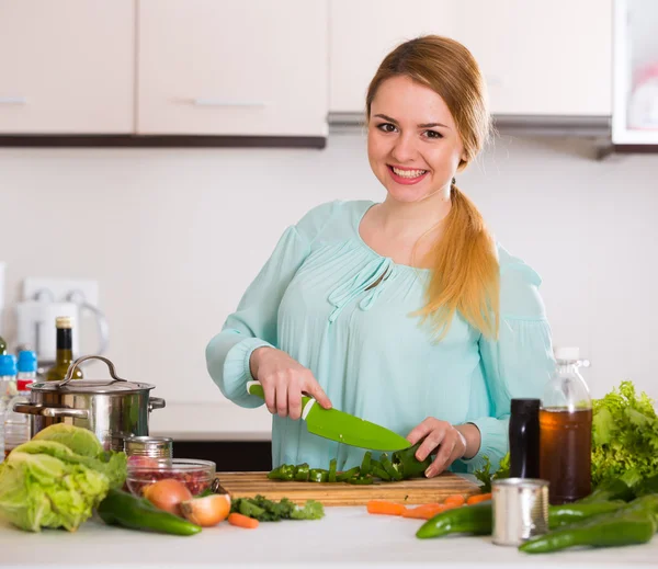 Jeune femme hachant laitue et herbes — Photo