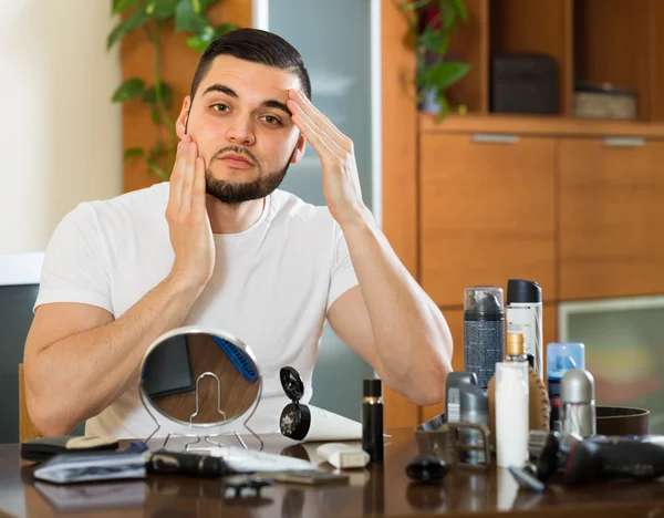 Homem aplicando creme facial em casa — Fotografia de Stock