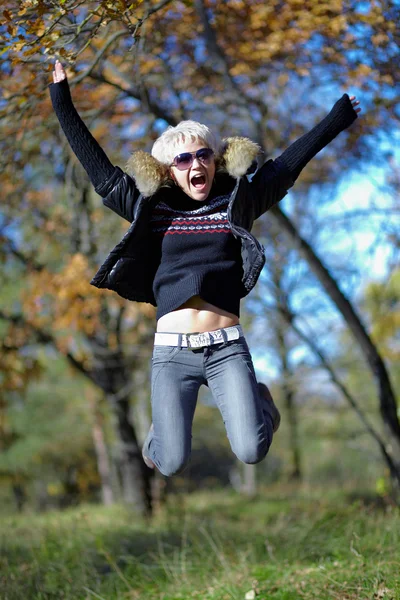 Blonde jumping on the background of autumn nature — Stock Photo, Image