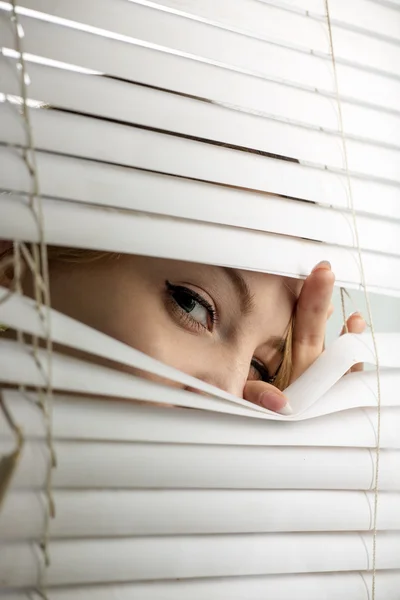 The woman looks through jalousie — Stock Photo, Image