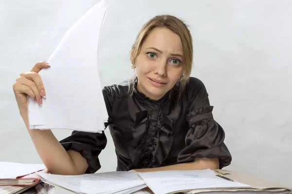 Эмоциональная девушка за столом с бумагами — стоковое фото