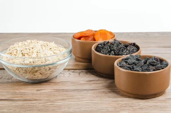 Oatmeal in a glass bowl and dried fruits — Stock Photo, Image