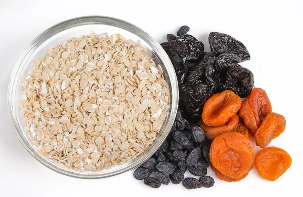 Oatmeal in a glass bowl and dried fruits — Stock Photo, Image