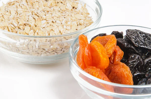 Oatmeal in a glass bowl and dried fruits — Stock Photo, Image