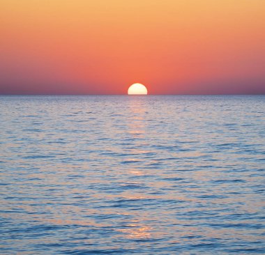 Deniz yüzeyinin altında büyük sarı güneşli parlak gün batımı