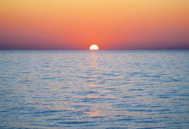 Deniz yüzeyinin altında büyük sarı güneşli parlak gün batımı