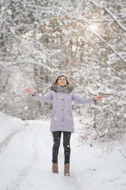 Mutlu genç kadın güneşli kış gününde karla oynuyor. Kızlar soğuk günlerde kışın tadını çıkarırlar. Ormanda karla oynamak..
