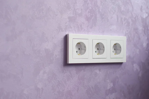 Wall socket and violet wall. After repair scene. Shallow depth-of-field