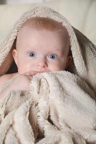 Baby with a towel after the shower in bed at home — Stockfoto