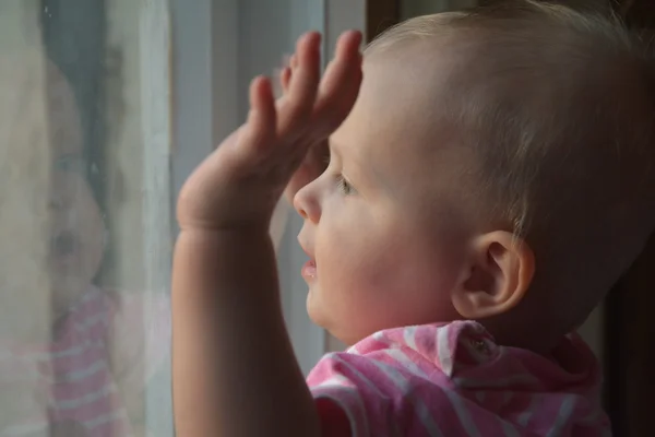 Niedliches Baby im Zimmer steht am Fenster Stockbild