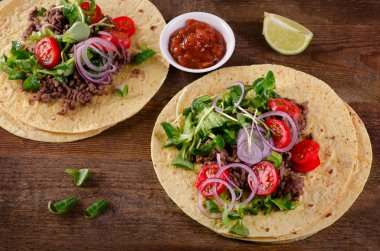 Ahşap masa üzerinde iki Meksikalı tacos